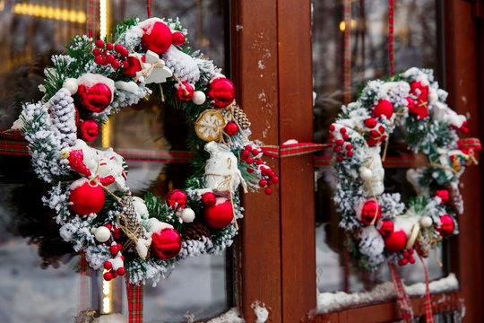 Christmas wreath on a door with red decoration, balls and snow