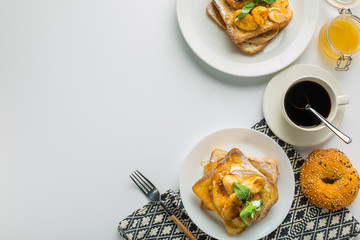 Toast with banana and mint, cup of coffee and bun with towel on white background top view with empty space