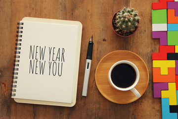 Top view of notebook and text NEW YEAR NEW YOU, cup of coffee over wooden desk.