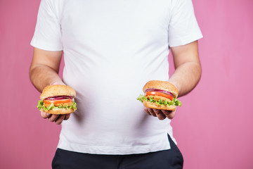 fat man with two tasty burgers. fast food and weight gain, gluttony, hunger, unhealthy eating