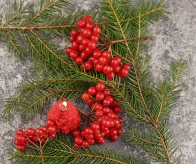 Winter still life with burning candle, spruce branches and a viburnum berries on a surface covered with hoarfrost