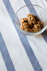 Walnuts in glass bowl on cloth, low angle view.