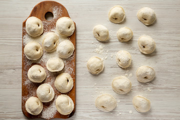 Homemade raw tortellini on white wooden background, top view. Flat lay, overhead.