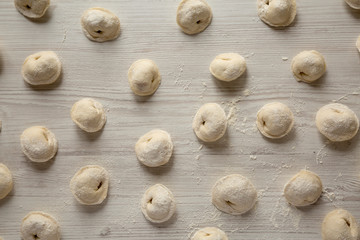 Homemade raw tortellini on white wooden table, overhead view. Top view, from above.