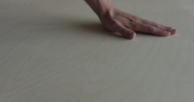 Slow motion man hand touches plywood to check surface