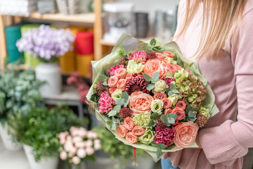 European floral shop. Bouquet of beautiful Mixed flowers in woman hand. Excellent garden flowers in the arrangement , the work of a professional florist.