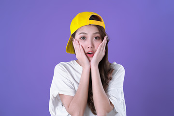 Asian hip hop woman shocking and hand up to her face, white t-shirt clothing and cap, purple background