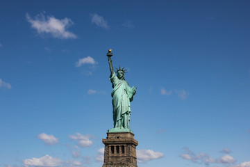 Fototapeta premium Statue of Liberty near New York city and Manhattan taken from a boat with a beautiful blue sky and some clouds in the background, United States