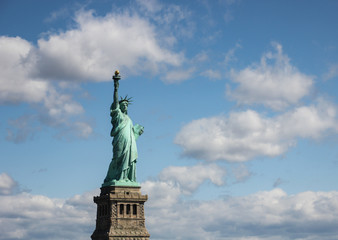 Obraz premium Statue of Liberty near New York city and Manhattan taken from a boat with a beautiful blue sky and some clouds in the background, United States