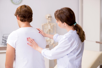 Obraz premium Male patient visiting young female doctor chiropractor 