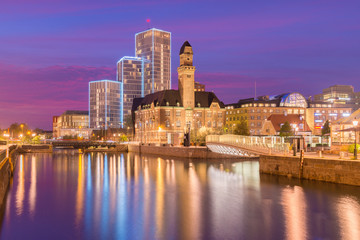 Fototapeta na wymiar Evening cityscape of Malmo, Sweden. Modern and old historical buildings reflected in the water. Picturesque sunset in a city