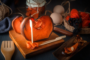 Slices of baked pumpkin with honey on a wooden board with eggs and various rural products