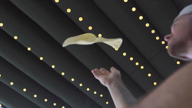 Pizza maker throwing pizza dough after rolling in pizzeria kitchen slow motion. Skilled pizzaillo making dough and throwing up in italian restaurant. Professional cheff cook cooking food