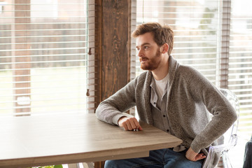 Serious applicant sitting by desk in boardroom and waiting for employer questions