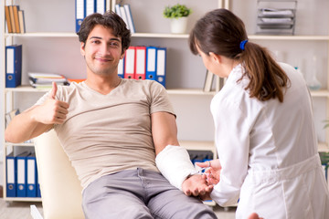 Obraz premium Young man with bandaged arm visiting female doctor traumatologis