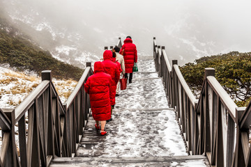 The staircase in the mountains and people in the red clothes climbing to the Cang Mountains...