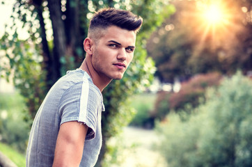 One handsome young man in urban setting in European city park, near a river
