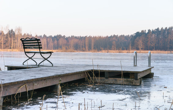 Einsamer Holzsteg am zugefrorenem See im Winter