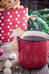 Red tea mug with cookies in Christmas decorations on a wooden table, selective focus