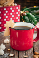 Red tea mug with cookies in Christmas decorations on a wooden table, selective focus