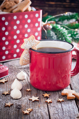 Red tea mug with cookies in Christmas decorations on a wooden table, selective focus