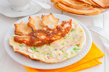 Omelet with crab sticks on a white plate with toast of white bread, horizontal
