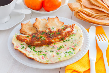 Omelet with crab sticks on a white plate with toast of white bread, horizontal