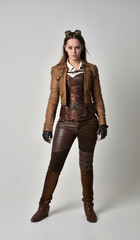 full length portrait of brunette  girl wearing brown leather steampunk outfit. standing pose, on...