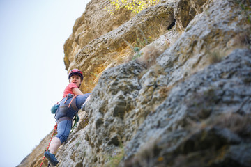 Photo of young sportswoman in protective helmet climbing on mountain