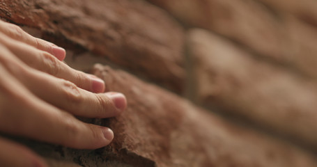 closeup man hand touching old brick wall