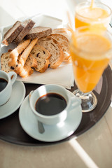 Beginning of a sunny good day. A cup of coffee, orange juice and fresh crispy pastries
