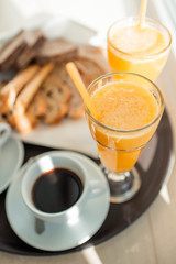 Beginning of a sunny good day. A cup of coffee, orange juice and fresh crispy pastries