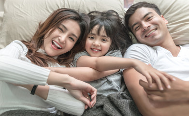 elevated view portrait of happy family lying on bed and looking up and holding hands