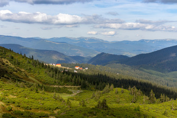 Fototapeta na wymiar Panoramic mountains view with village and clouds shadow on green forest valley. Carpathian mountains in perspective. Majesic rural landscape in Carpathains, Ukraine. Beautiful sky with clouds.