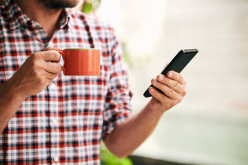 Modern man using cellphone and drinking coffee.