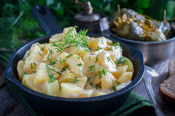 young potatoes cooked in sour cream in a cast iron pan, horizontal