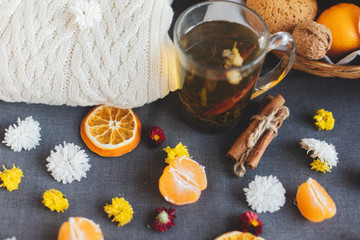 Tangerines, flowers, gingerbread, citrus in sraw basket, warm sweater, cup of tea and orange slices. Christmas winter background, wallpaper, greeting card. Top view, flat lay, background, copy spaces