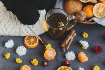 Tangerines, flowers, gingerbread, citrus in sraw basket, warm sweater, cup of tea and orange slices. Christmas winter background, wallpaper, greeting card. Top view, flat lay, background, copy spaces
