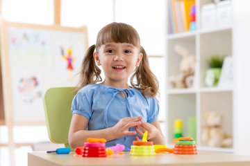 Fototapeta premium Children's creativity. Kid sculpts from clay. Adorable little girl moulds from plasticine on table in nursery