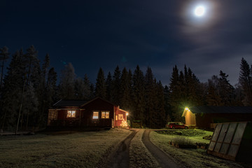 full moon shining over a little red cabin