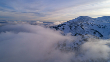 helicopter view of the peak of the mountain shrouded in fog at dawn