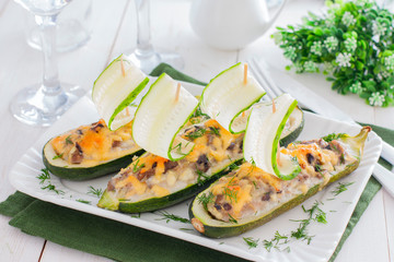 Festive stuffed with meat and mushrooms zucchini in the shape of boats decorated with fresh cucumber, horizontal