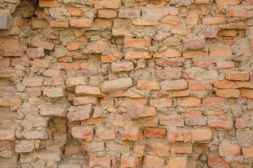 an old heavily destroyed red brick wall. rough surface texture