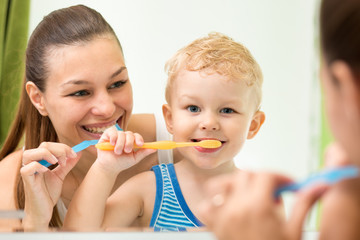 Pretty woman and her child son brushing their teeth and looking at miroor in bathroom