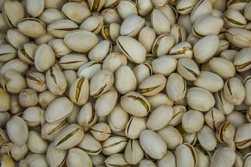 A lot of fresh white golden green pistachio nuts lie in a heap. natural surface texture