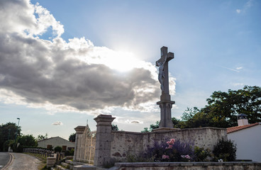 Fototapeta premium Statue Of Jesus On A Cross With Bright Sun Behind Clouds
