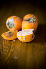frozen ripe persimmon in ice on wooden