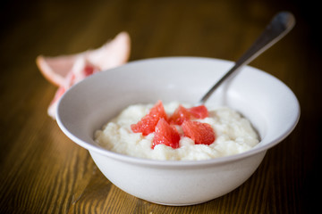 sweet boiled semolina porridge in a plate with slices of red grapefruit
