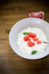 sweet boiled semolina porridge in a plate with slices of red grapefruit