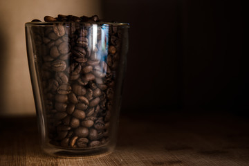 Coffee beans in glass cup on black background